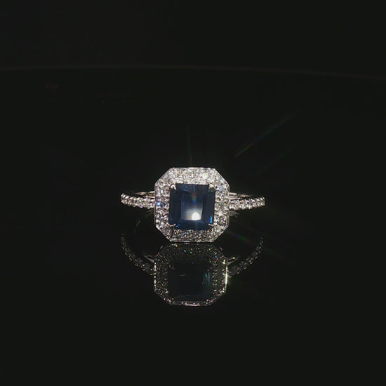Видео на луксозен годежен пръстен от бяло злато 14К със сапфир Emerald Cut 1.31 карата и естествени диаманти с общо тегло 0.31 карата модел LR3712S от Kirkorian Diamonds. Централният син сапфир с правоъгълна Emerald шлифовка е подчертан от блестящи естествени брилянти, създаващи впечатляващ контраст, изключителен блясък и елегантна визия. Изискан пръстен, подходящ за предложение за брак, годишнина или специален подарък.