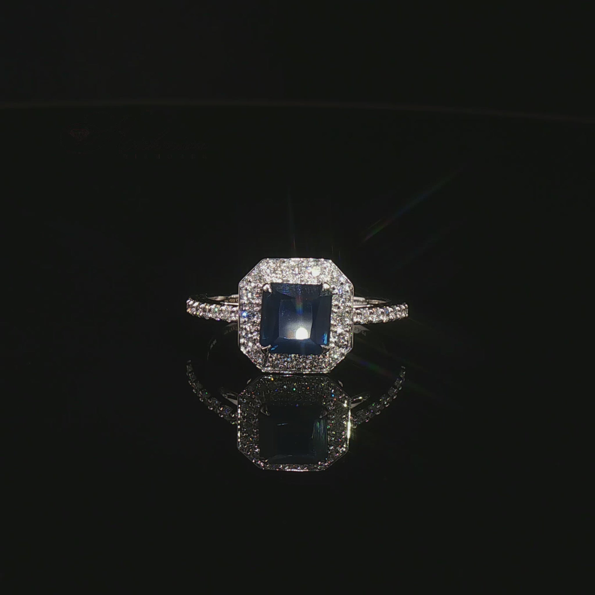 Видео на луксозен годежен пръстен от бяло злато 14К със сапфир Emerald Cut 1.31 карата и естествени диаманти с общо тегло 0.31 карата модел LR3712S от Kirkorian Diamonds. Централният син сапфир с правоъгълна Emerald шлифовка е подчертан от блестящи естествени брилянти, създаващи впечатляващ контраст, изключителен блясък и елегантна визия. Изискан пръстен, подходящ за предложение за брак, годишнина или специален подарък.